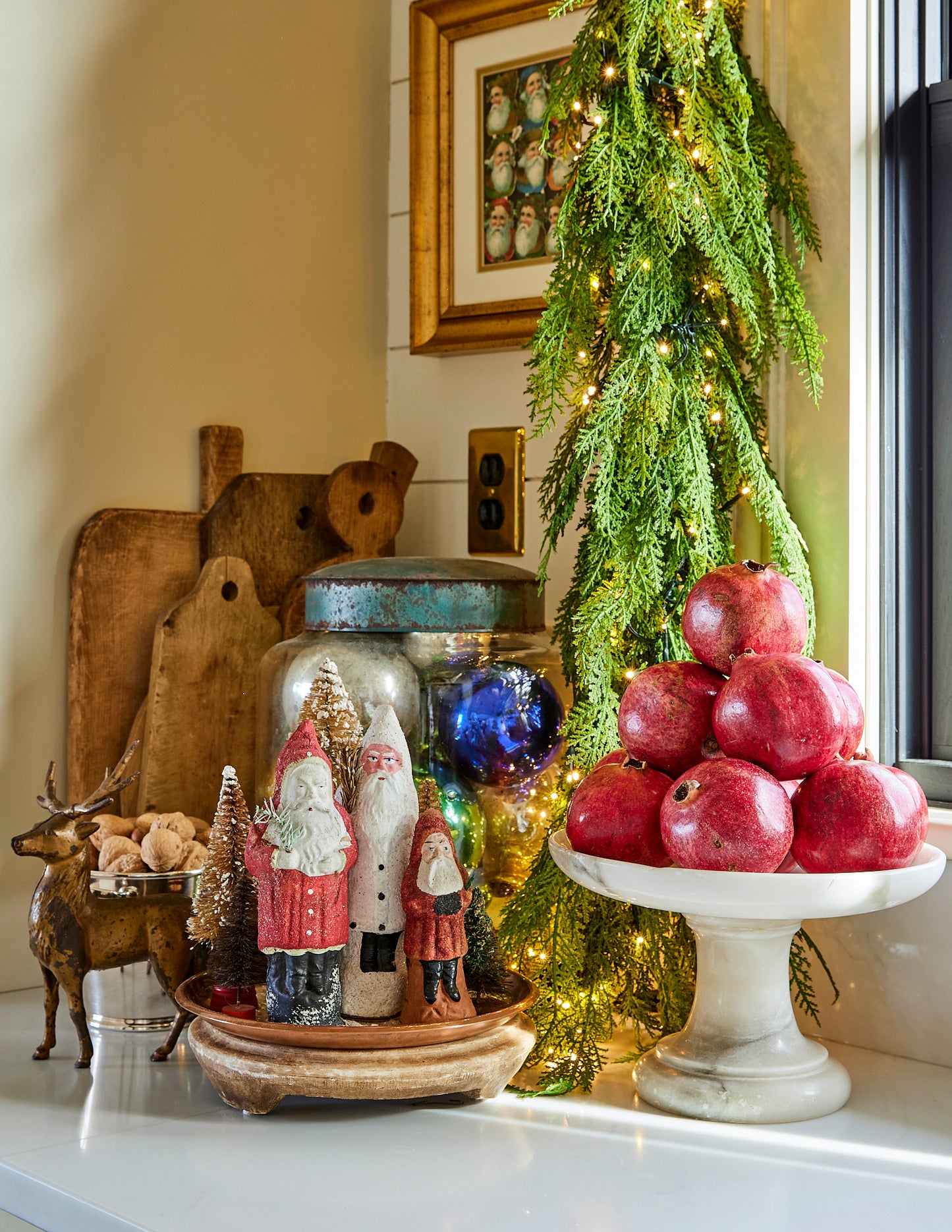 Decorative setup with pomegranates, Santa figurines, and a garland on a kitchen counter.