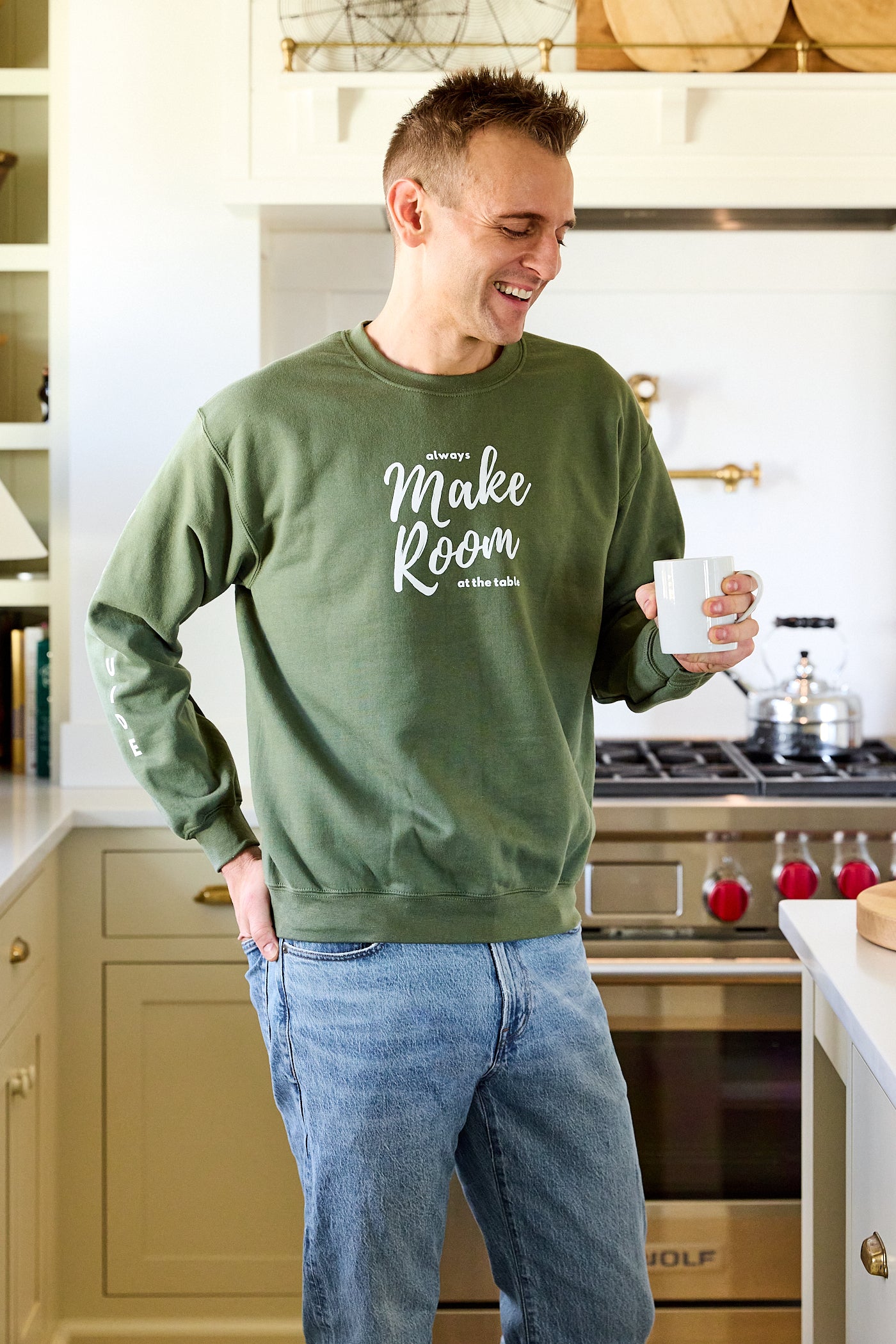 Kaleb Wyse wearing a green sweatshirt with the words "Always Make Room at the Table".