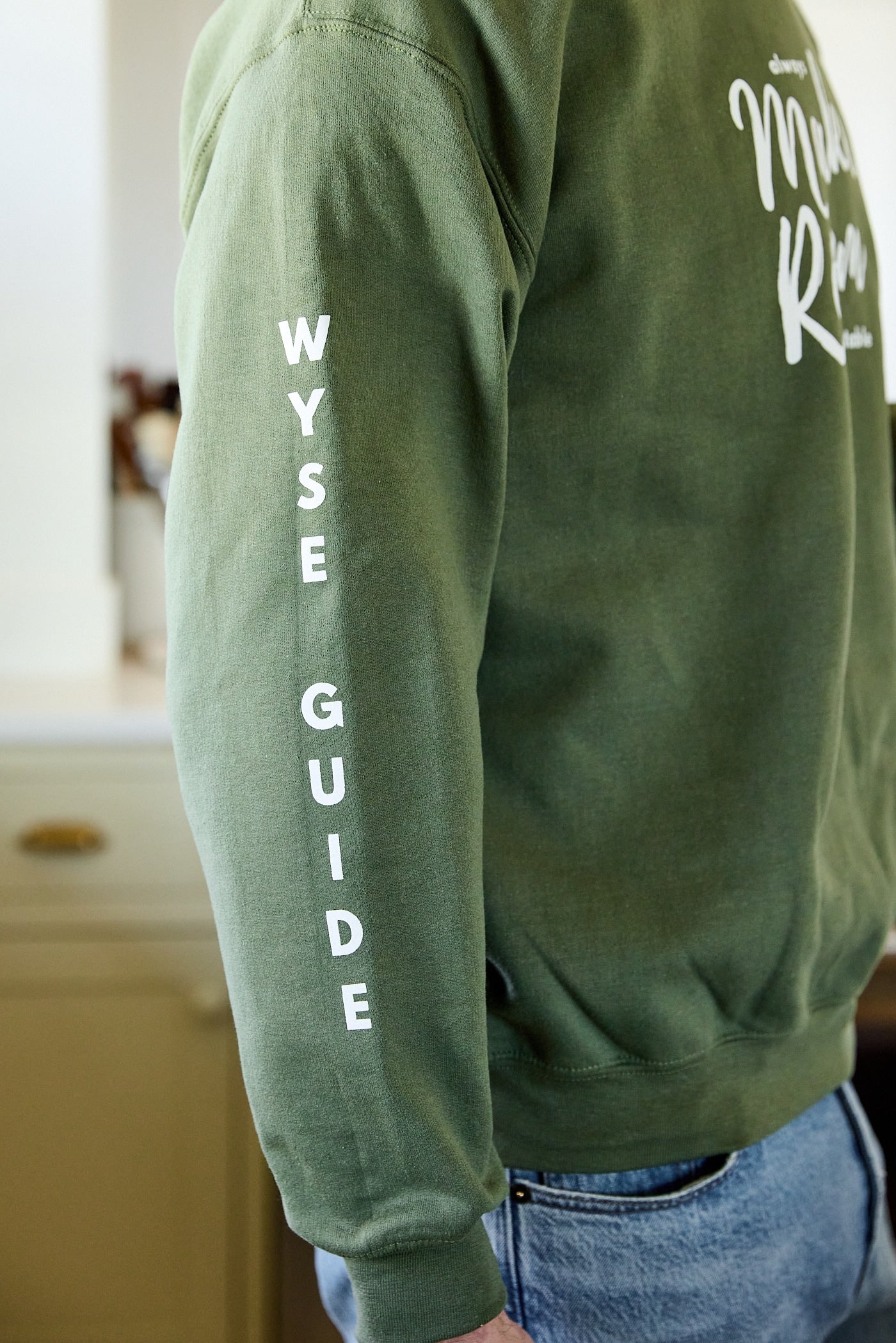 Green sweatshirt with the words Wyse Guide down the sleeve.