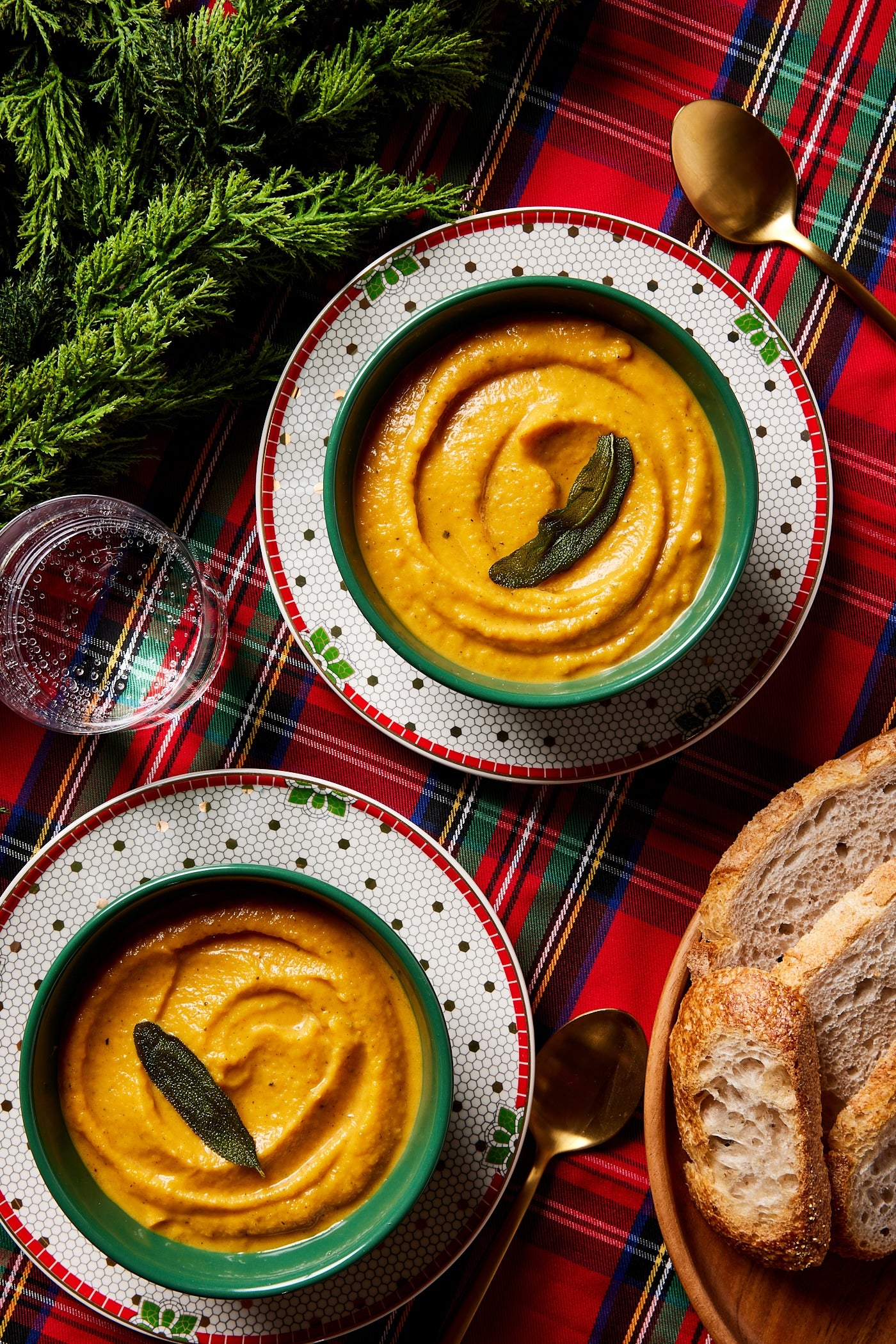 Festive holiday tablecloth with squash soup in green bowls.