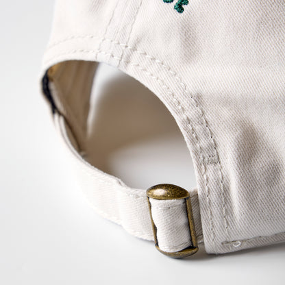 Close-up of a white cap with a gold buckle on a light gray background